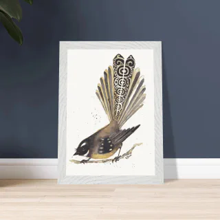 White framed dark pīwakawaka print leaning against a dark wall